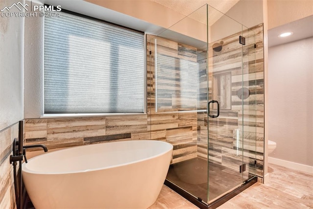 bathroom with independent shower and bath, tile walls, and toilet