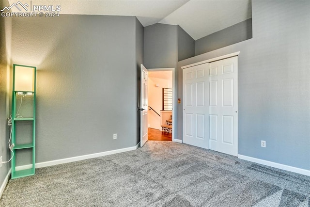 unfurnished bedroom with carpet, a closet, and vaulted ceiling