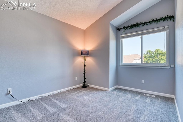 carpeted empty room featuring a textured ceiling and vaulted ceiling