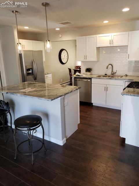 kitchen featuring appliances with stainless steel finishes, hanging light fixtures, white cabinetry, and dark hardwood / wood-style flooring