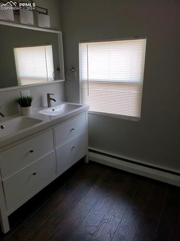 bathroom with vanity, baseboard heating, hardwood / wood-style floors, and a healthy amount of sunlight