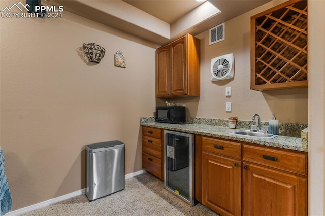 kitchen with light carpet, beverage cooler, light stone counters, and sink