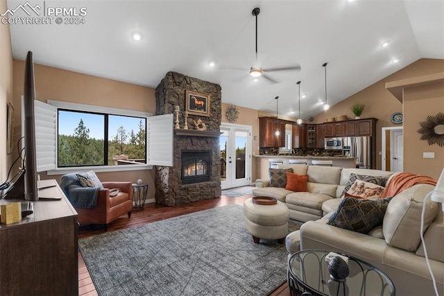 living room featuring a wealth of natural light, vaulted ceiling, ceiling fan, and a fireplace