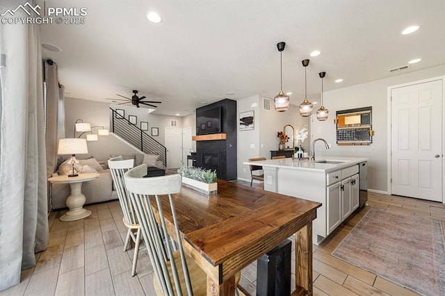 dining area with ceiling fan, a large fireplace, and sink