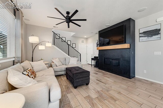 living room featuring a fireplace and ceiling fan