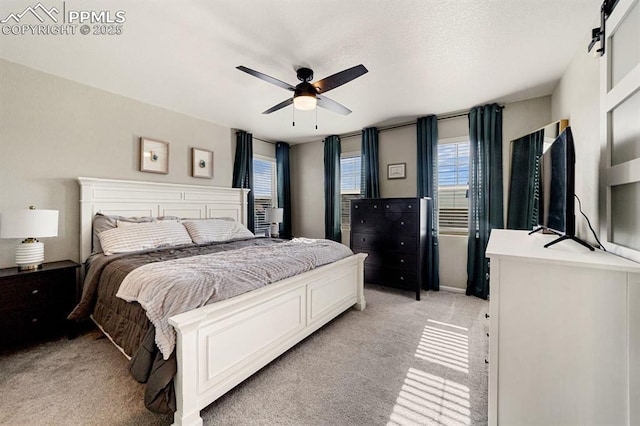 carpeted bedroom featuring ceiling fan and a barn door