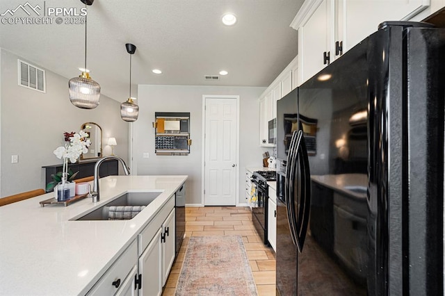 kitchen featuring sink, white cabinetry, hanging light fixtures, and black appliances