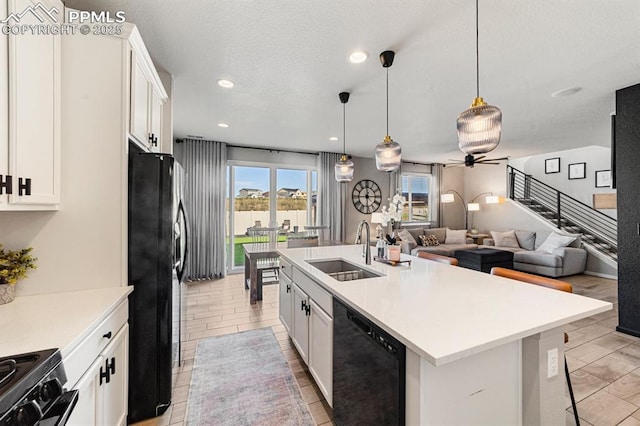 kitchen with an island with sink, white cabinetry, black appliances, and sink