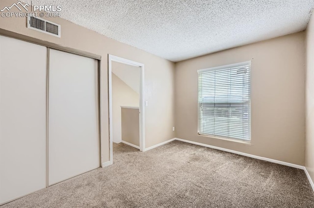 unfurnished bedroom with a closet, a textured ceiling, and carpet floors