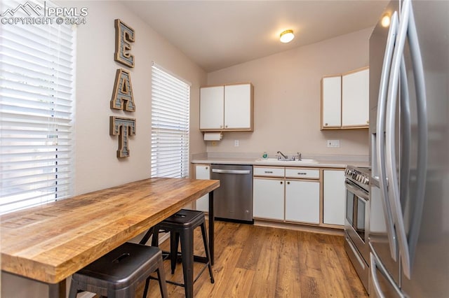 kitchen featuring light hardwood / wood-style flooring, stainless steel appliances, white cabinets, and a healthy amount of sunlight