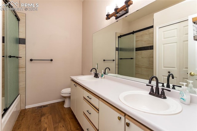 full bathroom featuring enclosed tub / shower combo, vanity, toilet, and hardwood / wood-style flooring