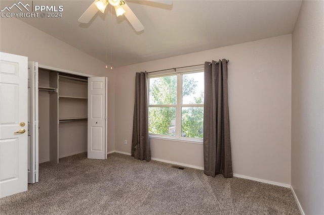 unfurnished bedroom with ceiling fan, a closet, vaulted ceiling, and carpet