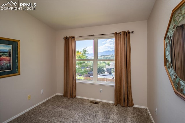 spare room featuring a mountain view and carpet floors