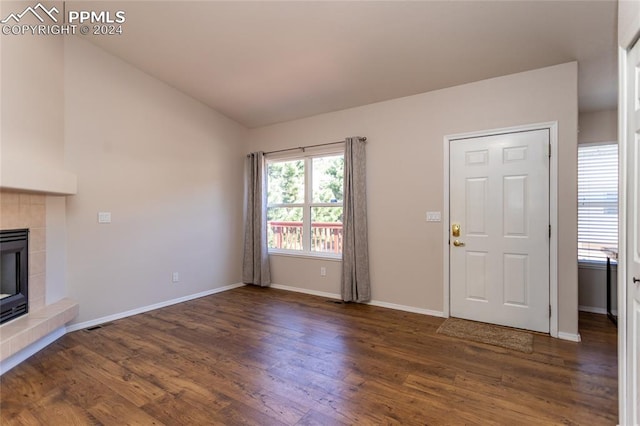 unfurnished living room featuring a tiled fireplace and dark wood-type flooring