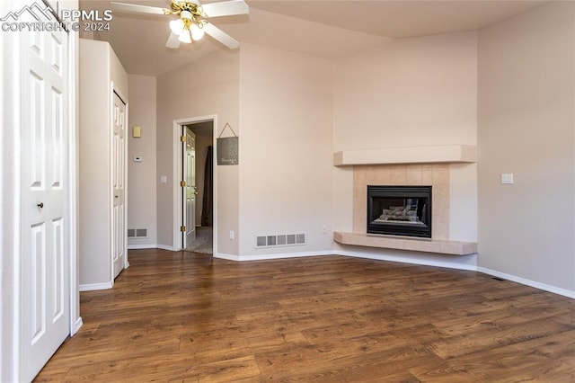 unfurnished living room featuring a tile fireplace, lofted ceiling, dark hardwood / wood-style flooring, and ceiling fan