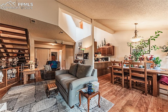 living room with a textured ceiling, high vaulted ceiling, and hardwood / wood-style flooring