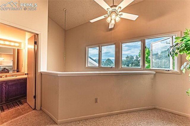 carpeted empty room with lofted ceiling, ceiling fan, plenty of natural light, and a textured ceiling