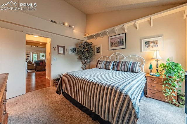 bedroom with a textured ceiling, carpet flooring, and vaulted ceiling