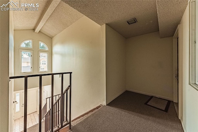 hallway featuring lofted ceiling with beams, a textured ceiling, and carpet floors