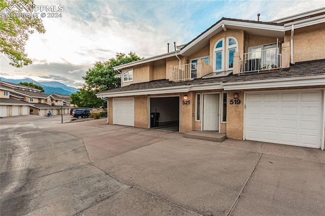 view of front of property featuring a balcony, a garage, a mountain view, and central air condition unit