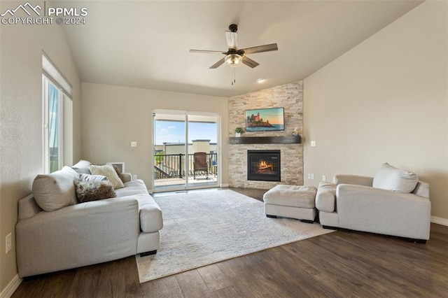 living room with ceiling fan, dark hardwood / wood-style flooring, lofted ceiling, and a stone fireplace