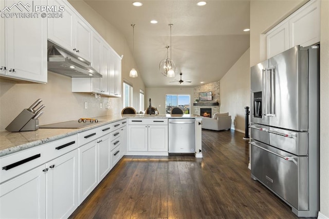 kitchen featuring stainless steel appliances, lofted ceiling, white cabinetry, and a stone fireplace