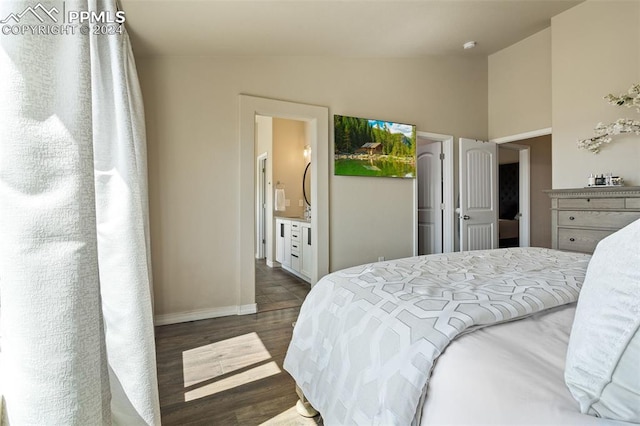 bedroom with vaulted ceiling, dark hardwood / wood-style floors, and ensuite bath