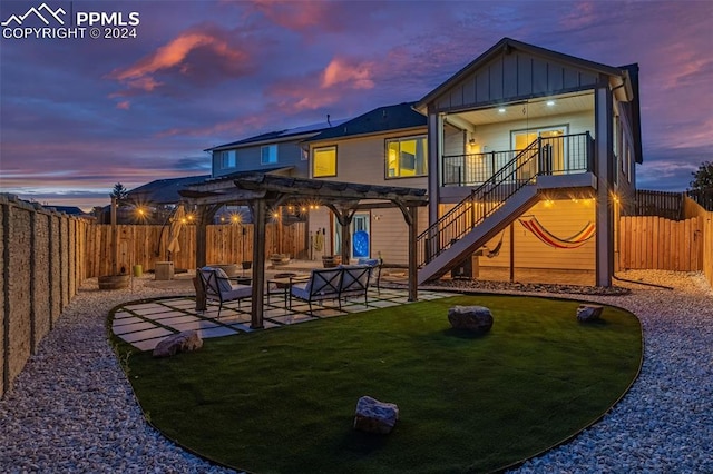 back house at dusk featuring a lawn, a pergola, a patio area, and outdoor lounge area