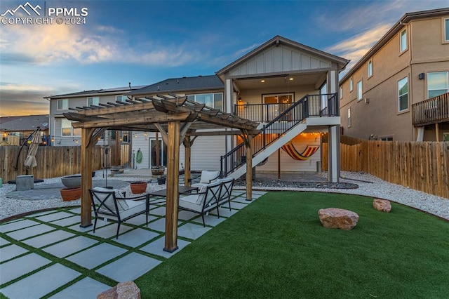 back house at dusk featuring a patio area, a lawn, and a pergola