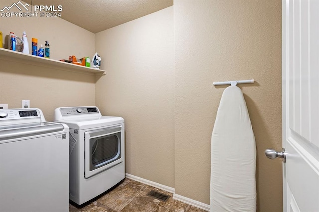 clothes washing area featuring washing machine and clothes dryer and a textured ceiling