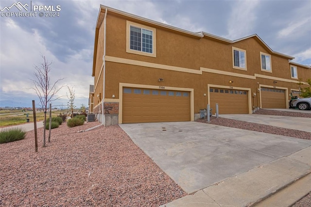 view of front of property featuring central air condition unit and a garage