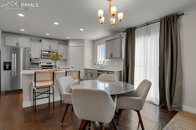 dining area with a notable chandelier, sink, and dark hardwood / wood-style flooring