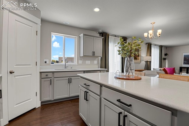 kitchen featuring hanging light fixtures, dark hardwood / wood-style flooring, gray cabinets, an inviting chandelier, and sink