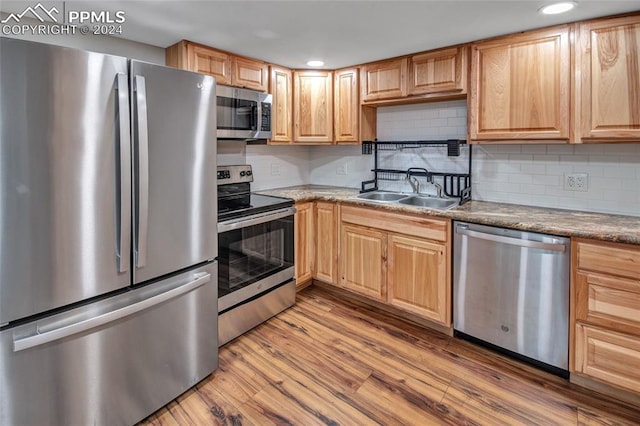 kitchen with backsplash, light brown cabinetry, stainless steel appliances, light hardwood / wood-style floors, and sink