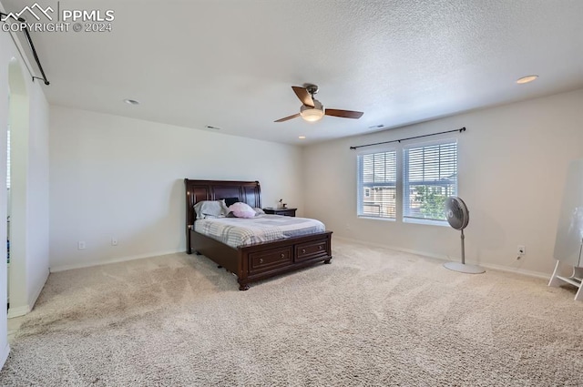 bedroom with ceiling fan, light carpet, and a textured ceiling