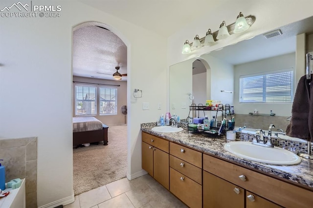 bathroom featuring a bathtub, tile patterned flooring, vanity, ceiling fan, and a textured ceiling