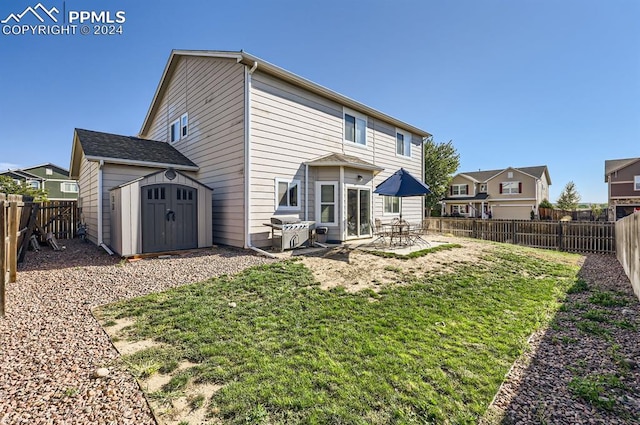 back of property with a storage shed, a yard, and a patio area