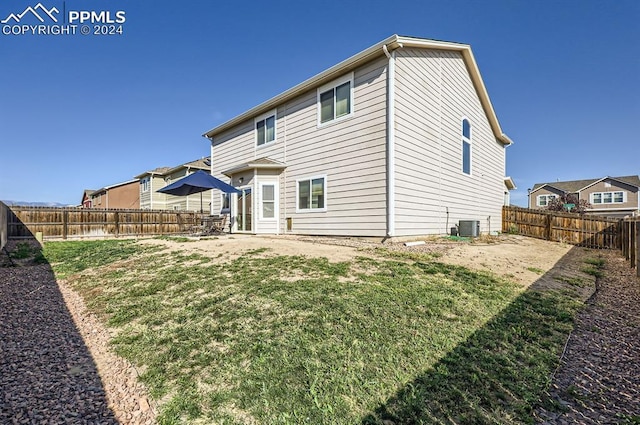 rear view of property featuring central AC unit and a yard