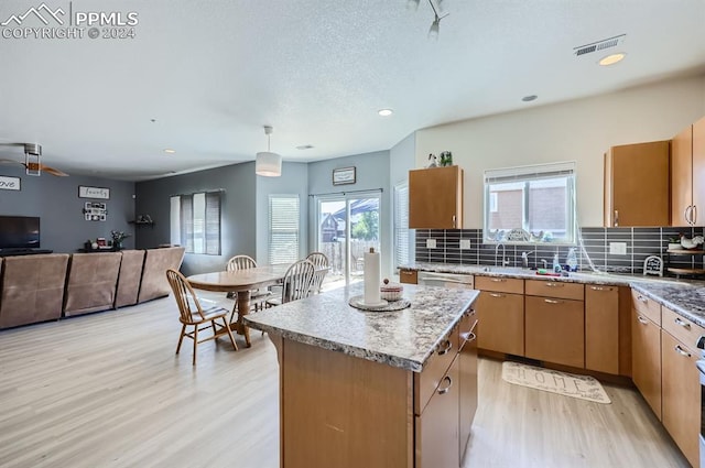 kitchen featuring tasteful backsplash, hanging light fixtures, light hardwood / wood-style floors, and a kitchen island