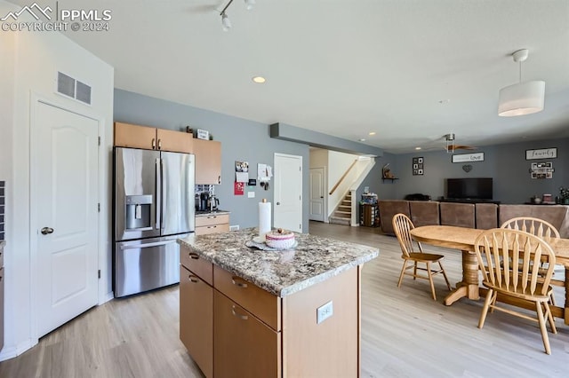 kitchen featuring light stone countertops, a kitchen island, light hardwood / wood-style floors, and stainless steel refrigerator with ice dispenser