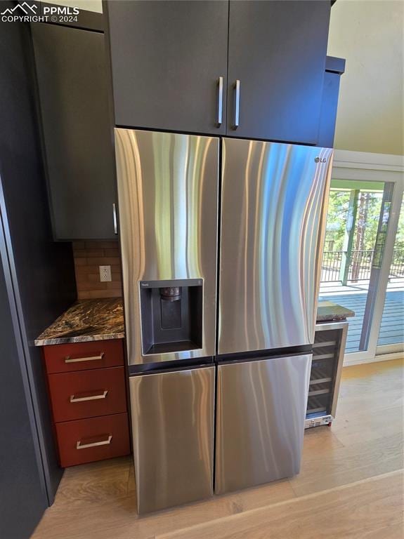 kitchen featuring stainless steel fridge, dark stone countertops, decorative backsplash, and light hardwood / wood-style floors