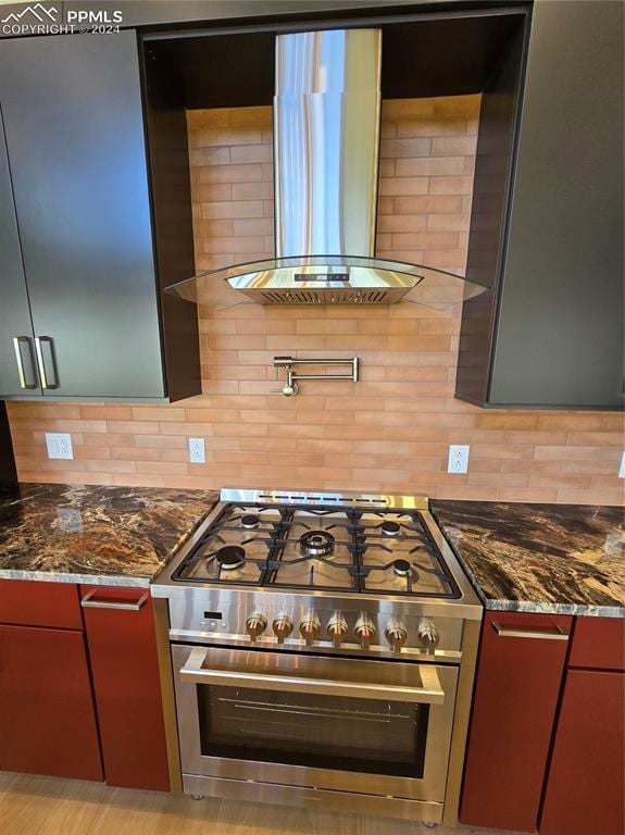 kitchen featuring dark stone counters, backsplash, range with two ovens, and extractor fan