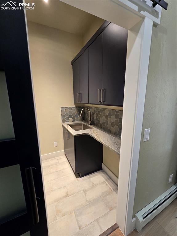 kitchen featuring a baseboard heating unit, decorative backsplash, and sink