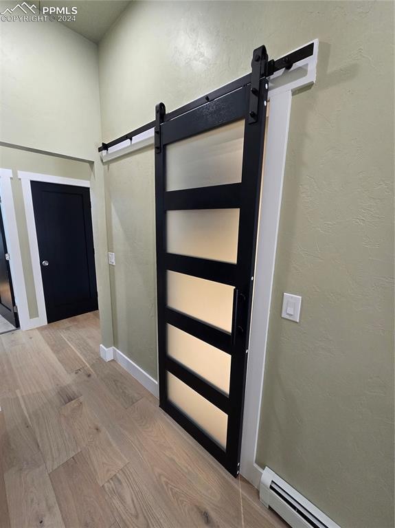 interior space featuring a baseboard heating unit, light hardwood / wood-style flooring, and a barn door