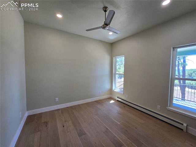 unfurnished room with a baseboard heating unit, ceiling fan, and wood-type flooring