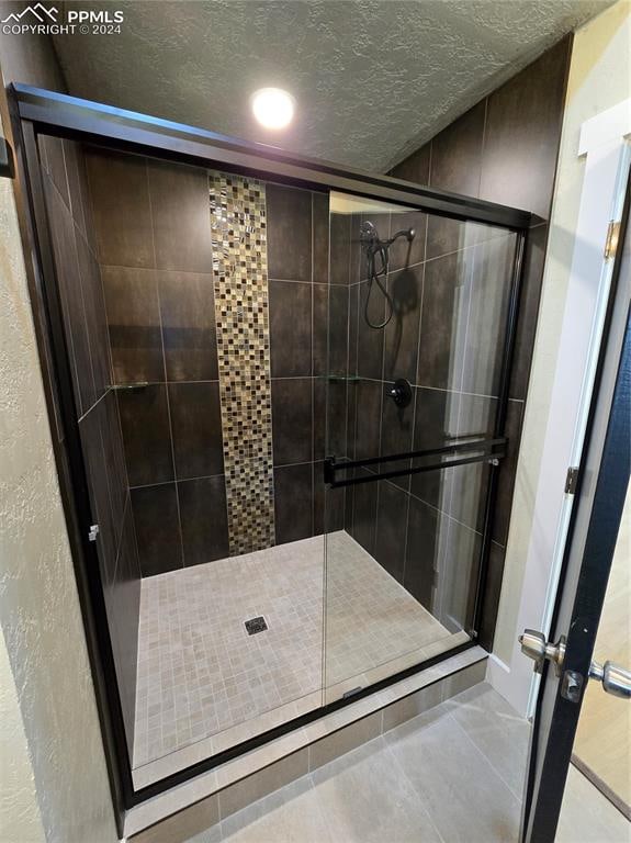 bathroom featuring tile patterned floors, a textured ceiling, and a shower with shower door