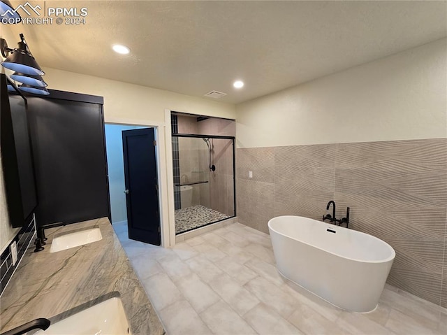 bathroom with vanity, tile walls, and independent shower and bath