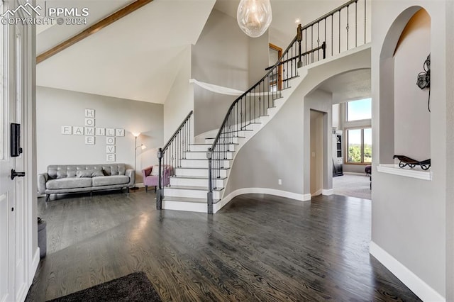 foyer entrance with dark wood-type flooring, beam ceiling, and high vaulted ceiling