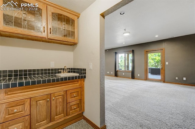 interior space featuring tile countertops, sink, and carpet