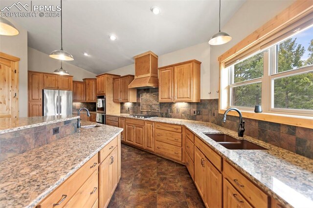 kitchen featuring custom exhaust hood, sink, light stone countertops, hanging light fixtures, and appliances with stainless steel finishes